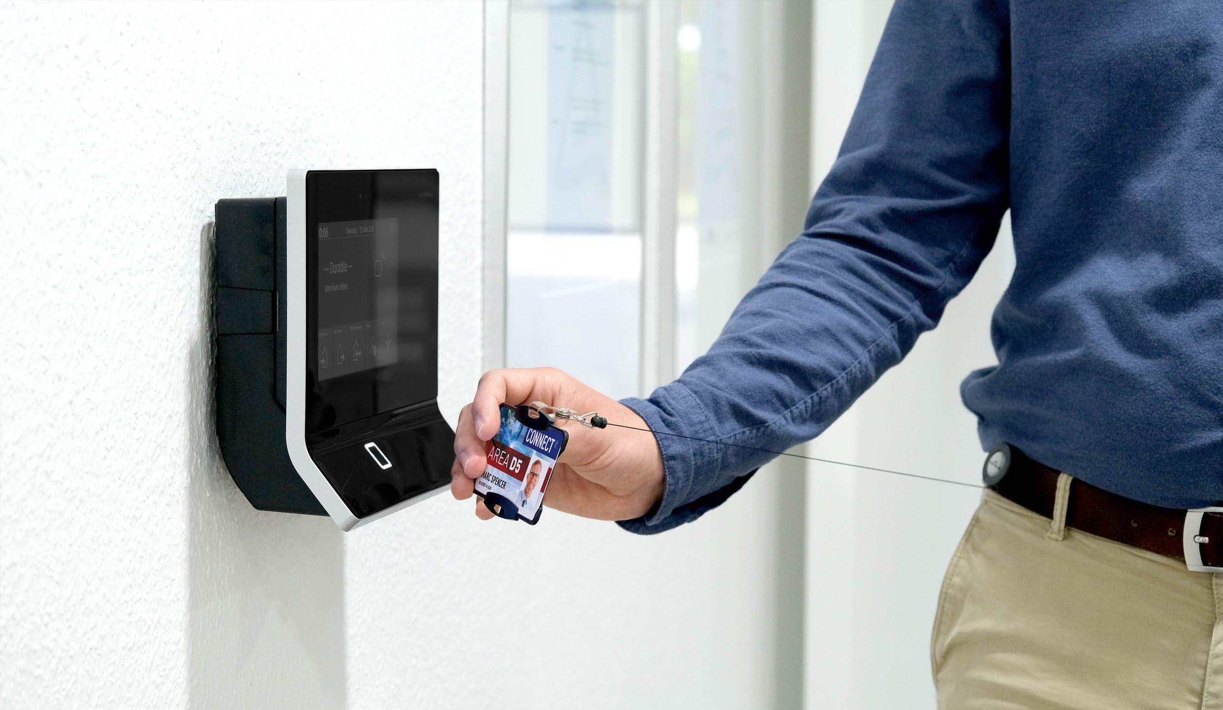 Employee using access card at wall-mounted security reader for office entry