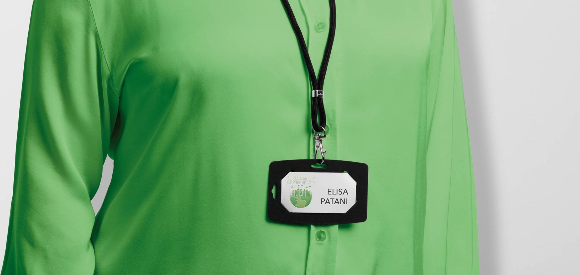 Black lanyard with ID badge holder for Sustainability Conference, worn on green shirt
