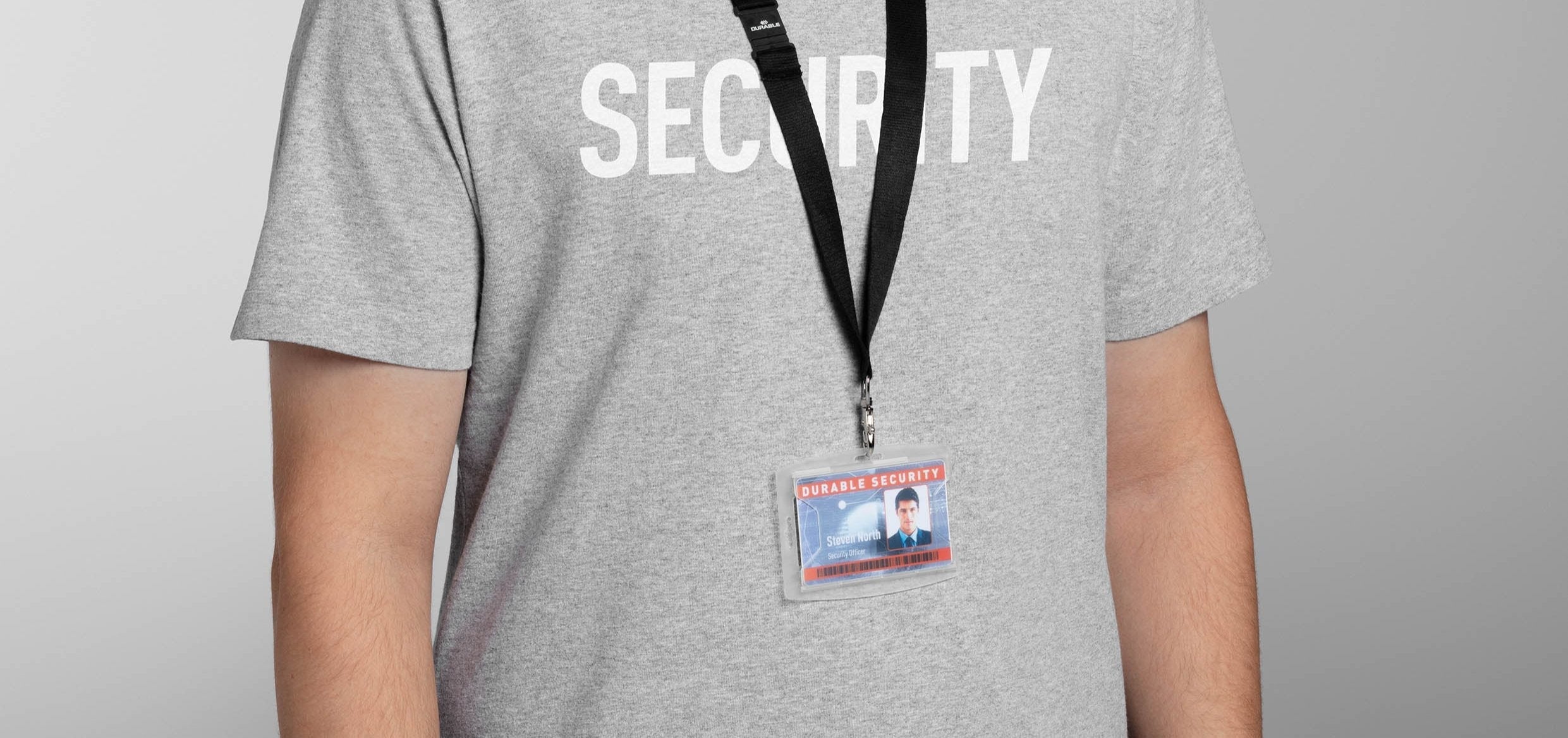 Security officer wearing gray shirt with ID badge on lanyard, clear holder with photo and name