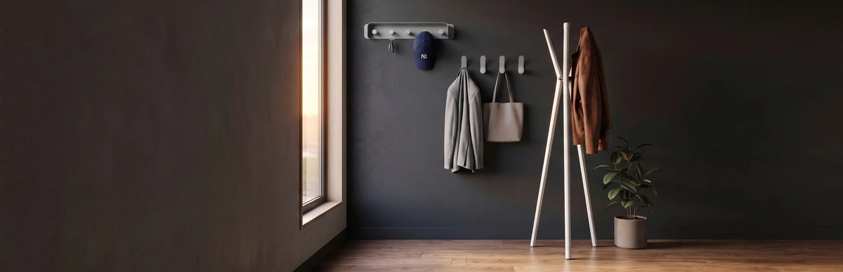 A dark entryway scene with a coat rack holding a brown jacket, a small potted plant, and a wall-mounted rack with a gray bag and a blue cap, set against a dark wall beside a window.